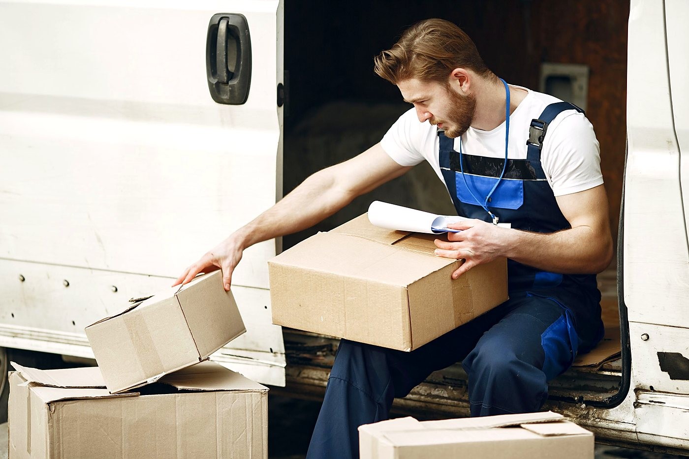 serv-logistica-van Profissional confere volumes ao lado de uma van de carga